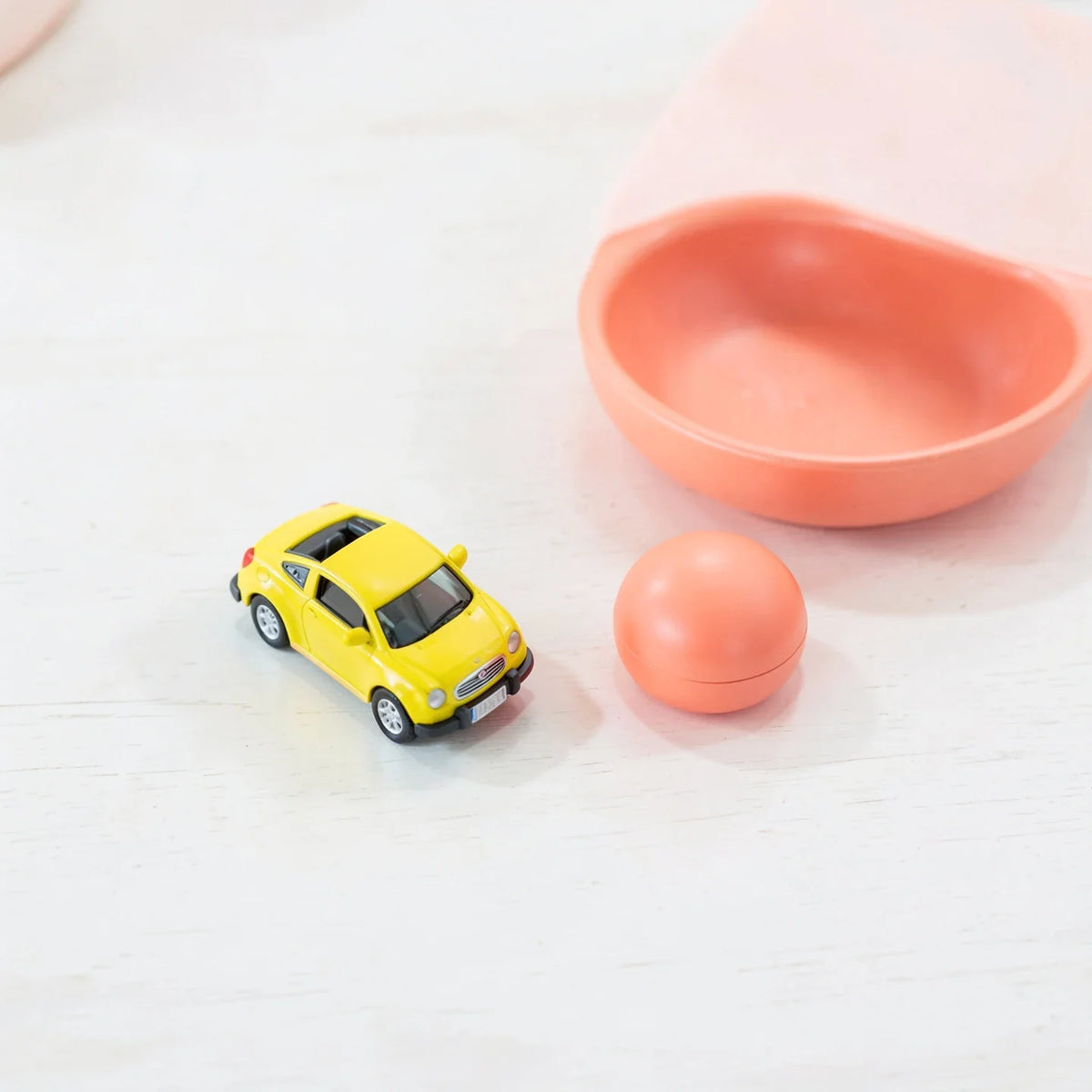 A small toy car and a desk fidget toy on a wooden desk